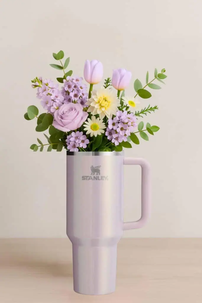 Lavender Stanley tumbler filled with a pastel bouquet of tulips, roses, daisies, and greenery, styled as a unique holiday gift idea for health and wellness lovers.