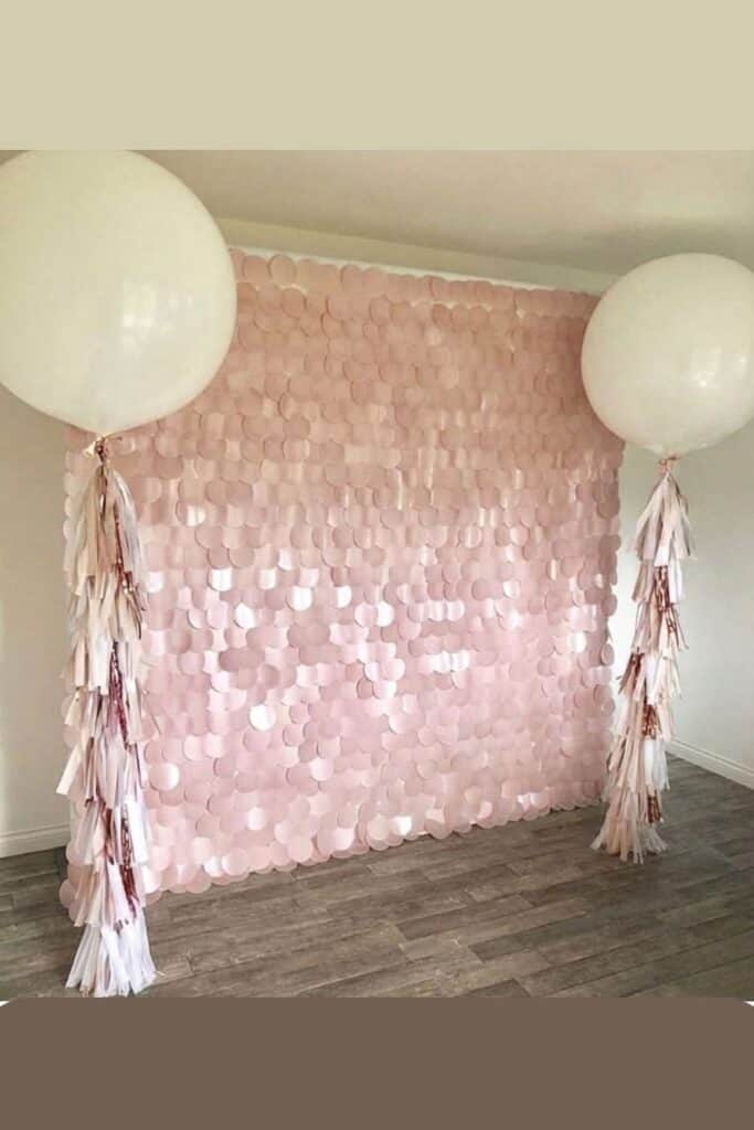 Blush pink sequin photo backdrop with large white balloons and tassel garlands for party decor