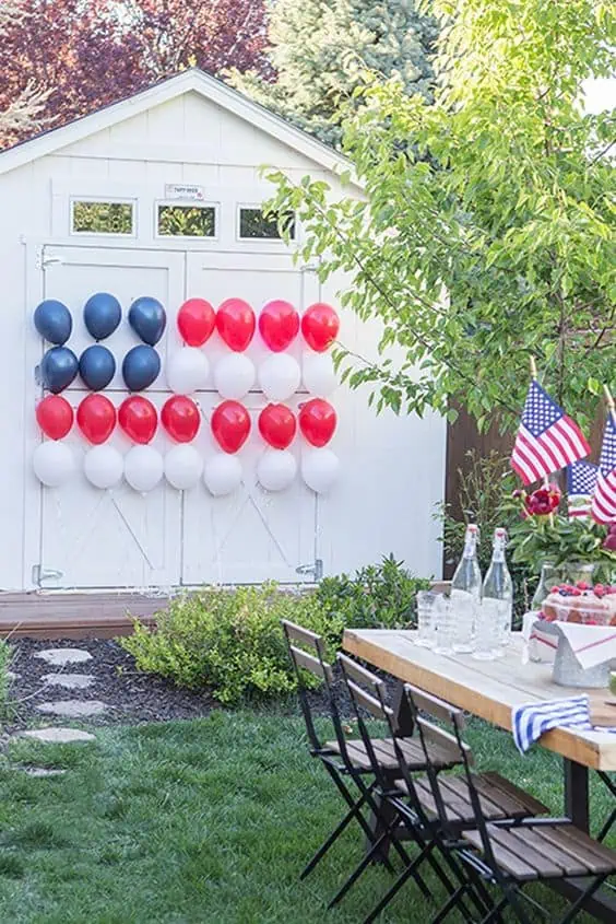 4th of July backyard setting with red, white, and blue balloons in a flag shape decoration on the barn