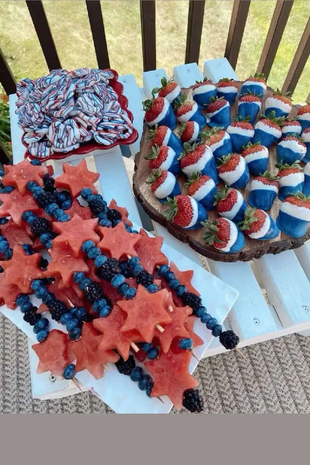 4th of July party food table with star shaped watermelon and blueberry fruit skewers, red white and blue pretzels, and red white and blue dipped strawberries
