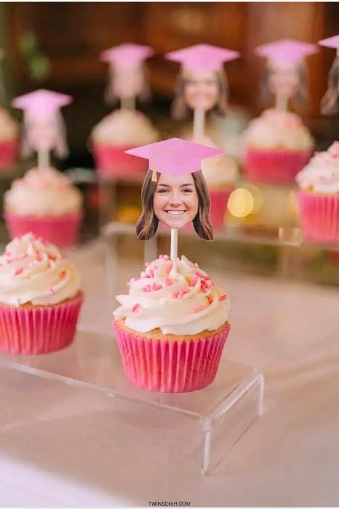 Pink graduation cupcakes with white frosting and personalized photo toppers wearing graduation cap
