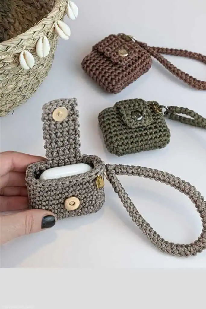 Free crochet AirPods case pattern featuring a button flap and wristlet strap, made with sturdy textured stitches in neutral yarn. A beginner-friendly DIY gift idea trending THIS YEAR for handmade accessories and tech storage.