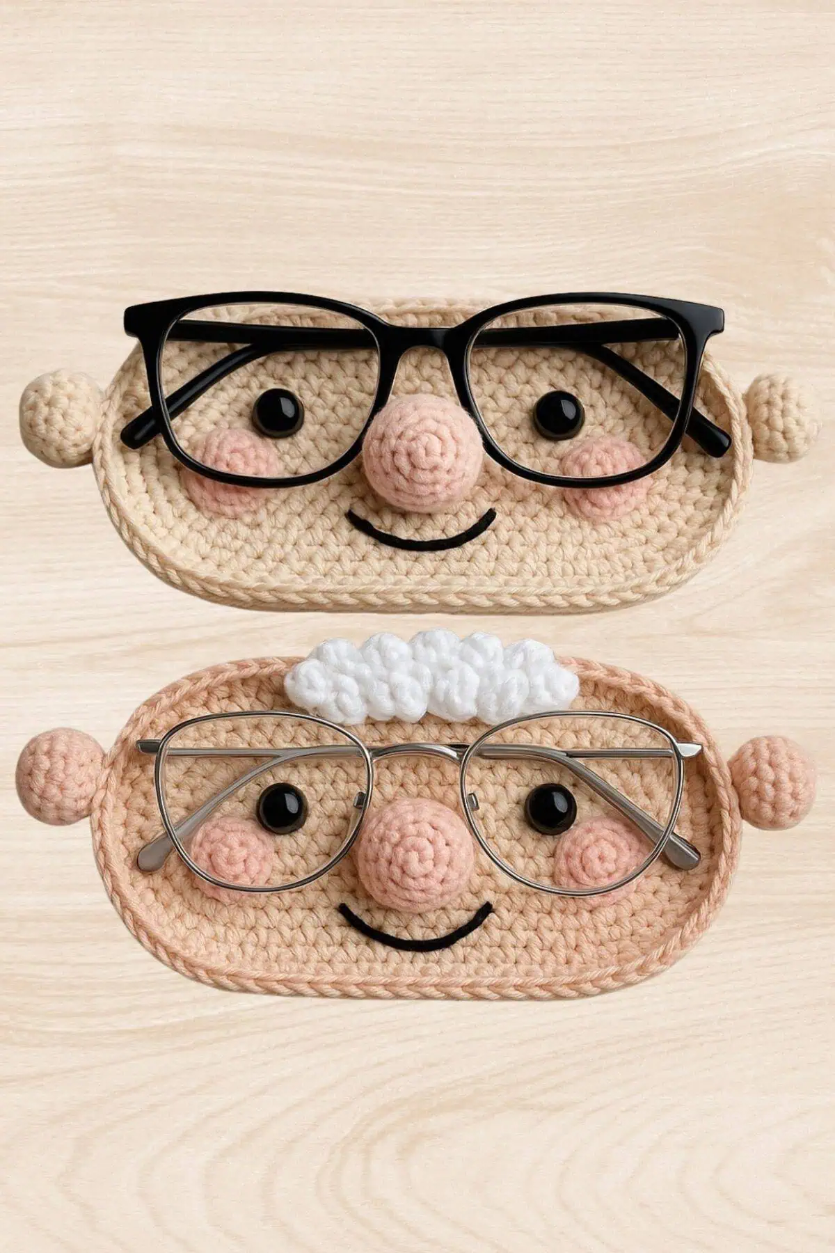Two crocheted eyeglass holders shaped like smiling grandma and grandpa faces, complete with pink cheeks, noses, and glasses, made from yarn in soft beige tones.