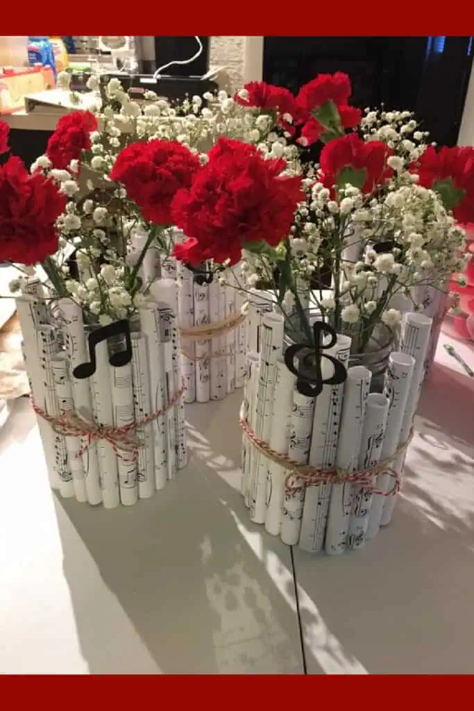 Graduation Party centerpiece made with a mason jar and rolled up sheet music with red flowers