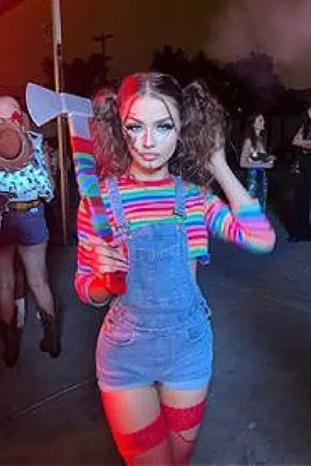 Woman with curly hair in Chucky Halloween costume holding a fake axe