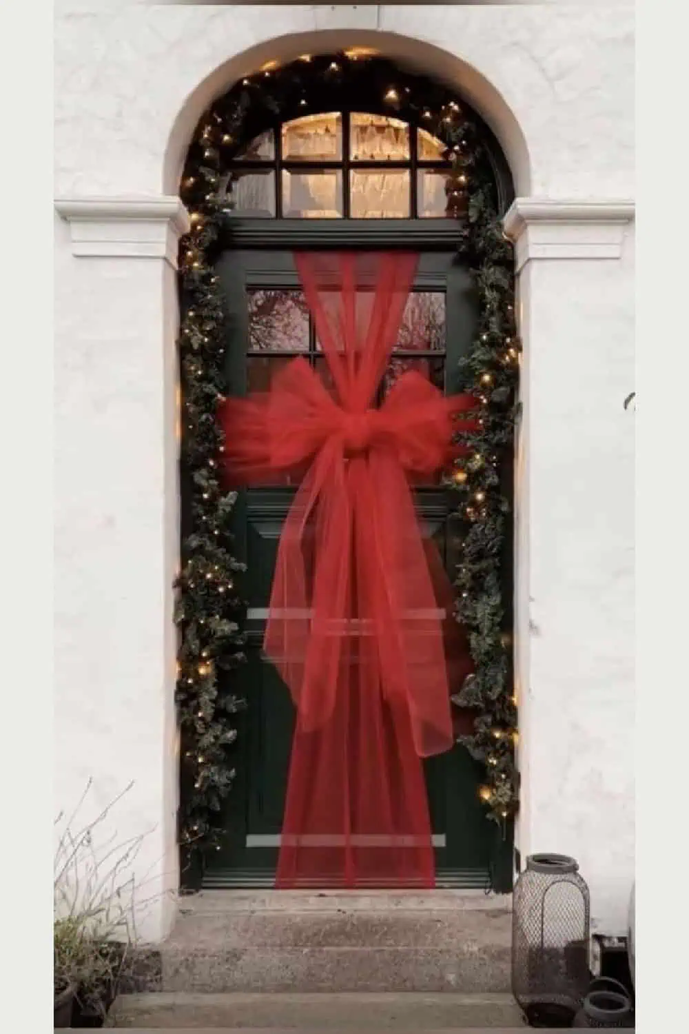 Front door wrapped with a large tulle bow and Christmas garland