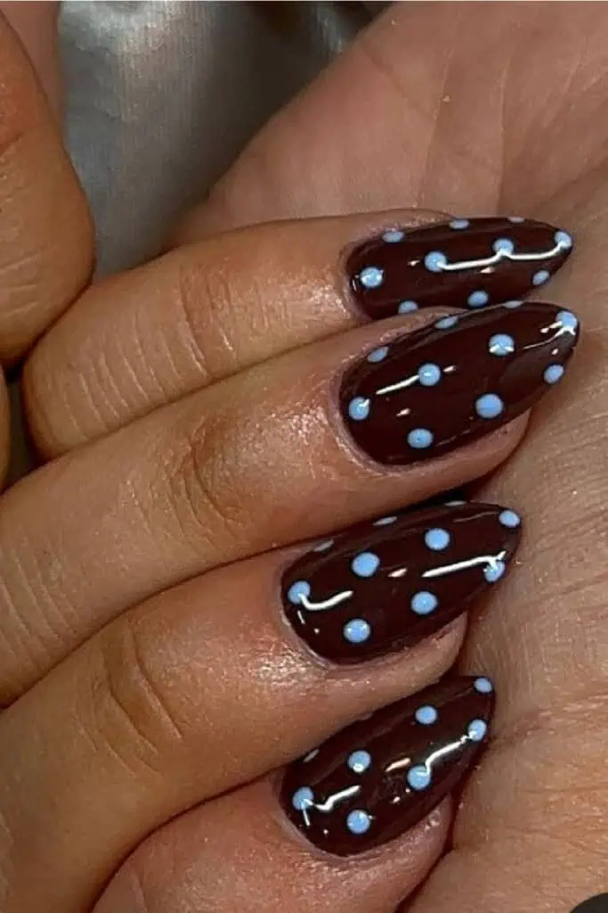 Brown almond-shaped nails with light blue polka dot nail art. Cute and trendy September nail design with a fun fall aesthetic.