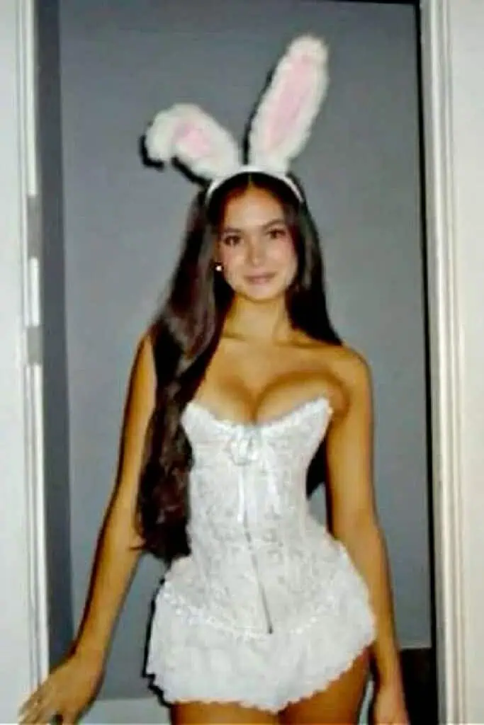 Woman wearing a white bunny costume with fluffy ears, lace corset, and mini skirt. Sexy Halloween bunny costume idea for women.