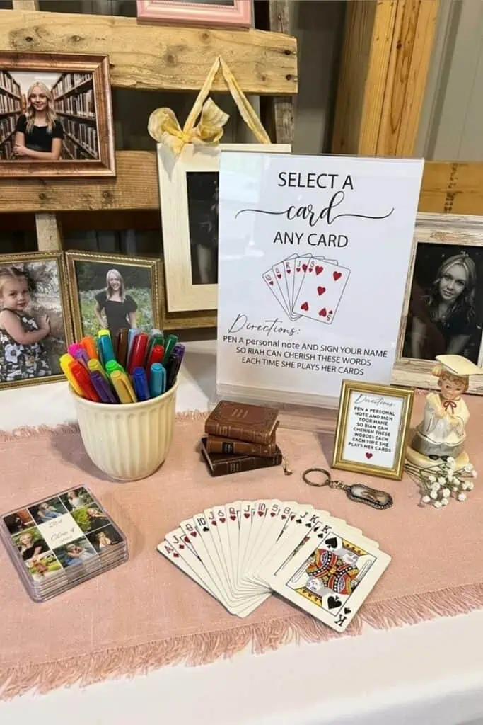 Graduation party guest book idea with deck of cards, markers, and framed photos on a decorated table