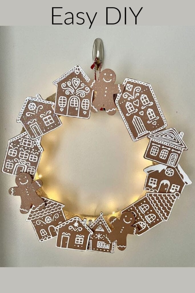 DIY gingerbread Christmas wreath made with paper gingerbread houses, gingerbread men, and twinkle lights. Easy festive holiday décor idea