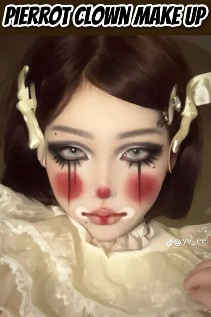 Close-up of a woman wearing Pierrot clown makeup with dramatic black eyeliner, red blush, a small red nose, and white painted lips, styled with vintage accessories and soft lighting.