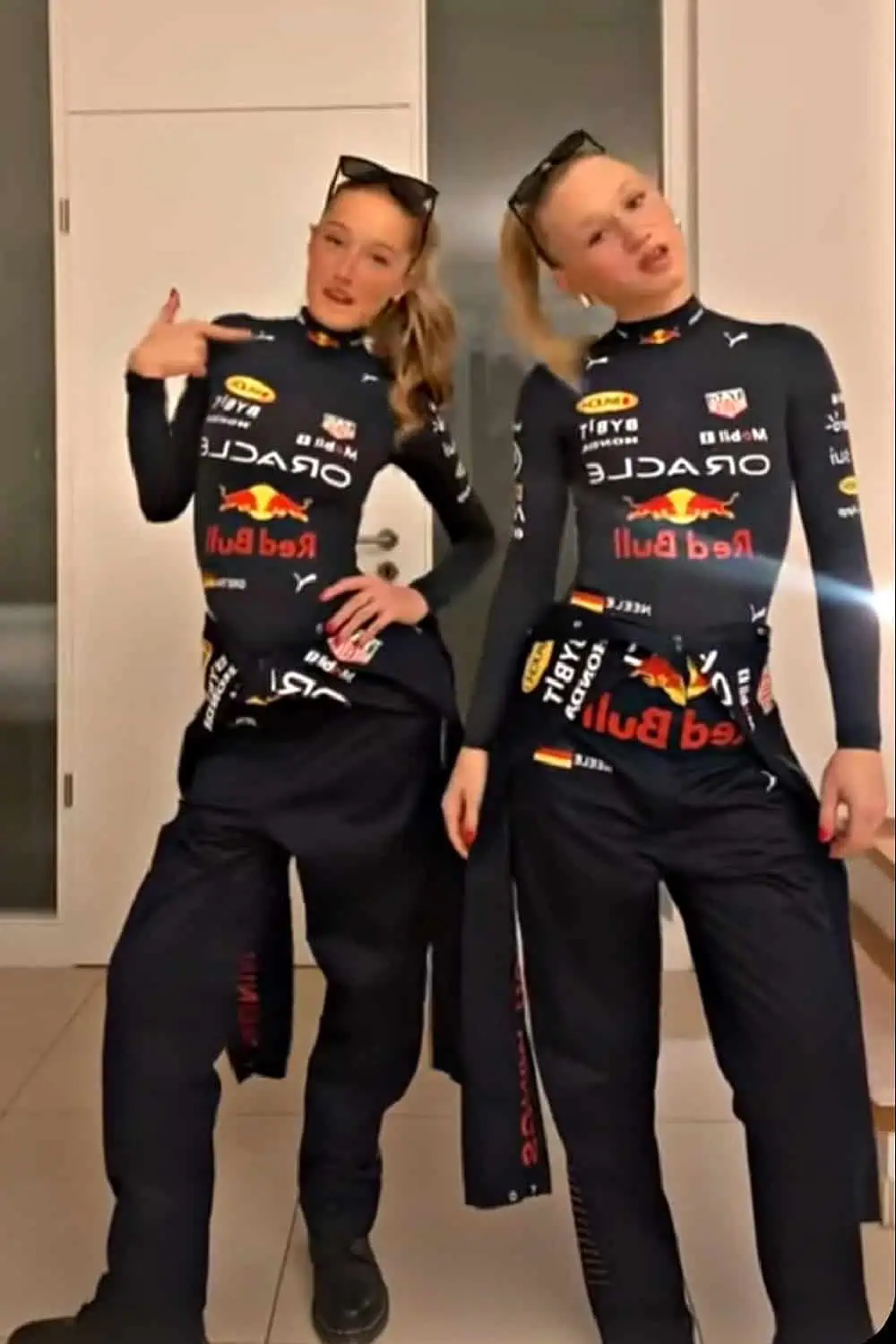 Two women dressed in matching Red Bull racing-inspired outfits with sunglasses, posing as race car drivers — fun and creative duo Halloween costume idea for women.