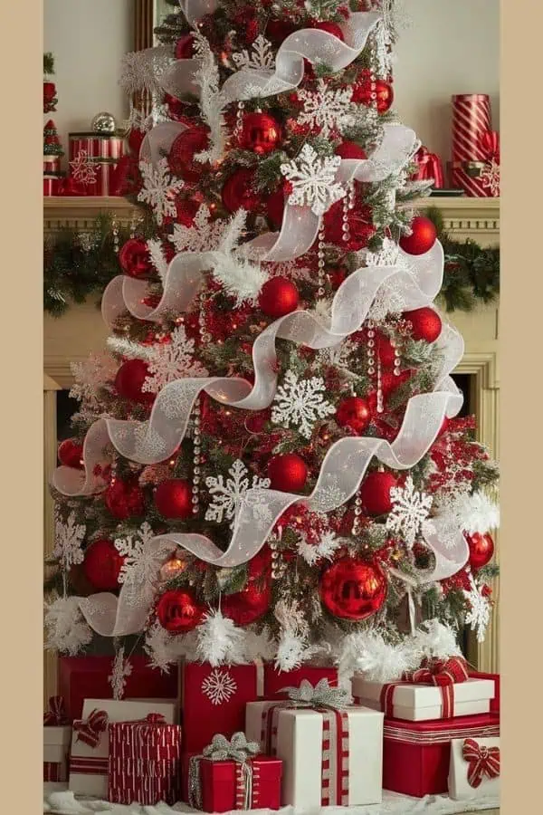 Red and white Christmas tree decorated with White mesh ribbon spiraled, large glittery snowflakes, white mesh garland, hanging faux crystal ornaments, and red ball ornaments. This trending this year tree theme features a bold color palette, elegant ribbon swags, and matching wrapped gifts for a perfectly coordinated holiday look.