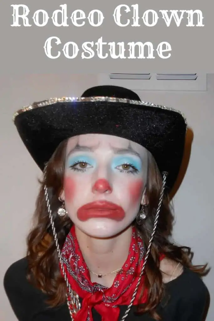 Person wearing a rodeo clown costume featuring bright blue eyeshadow, exaggerated red clown makeup, a black glittery cowboy hat with silver trim, and a red bandana around the neck. The look combines western and clown elements for a creative and humorous Halloween or costume party outfit.
