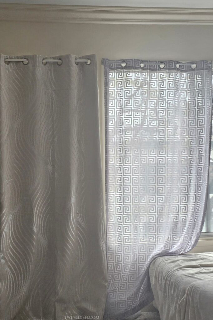 beige blackout curtains and gray patterned sheer curtains hanging beside a dorm room bed for privacy, light control, and cozy dorm decor.