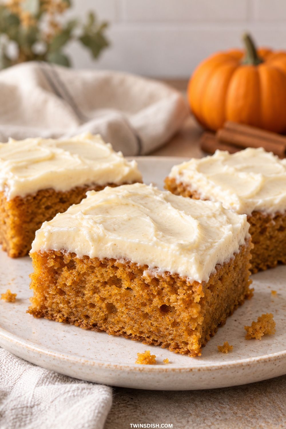 Easy pumpkin bars with cream cheese frosting arranged on a plate.