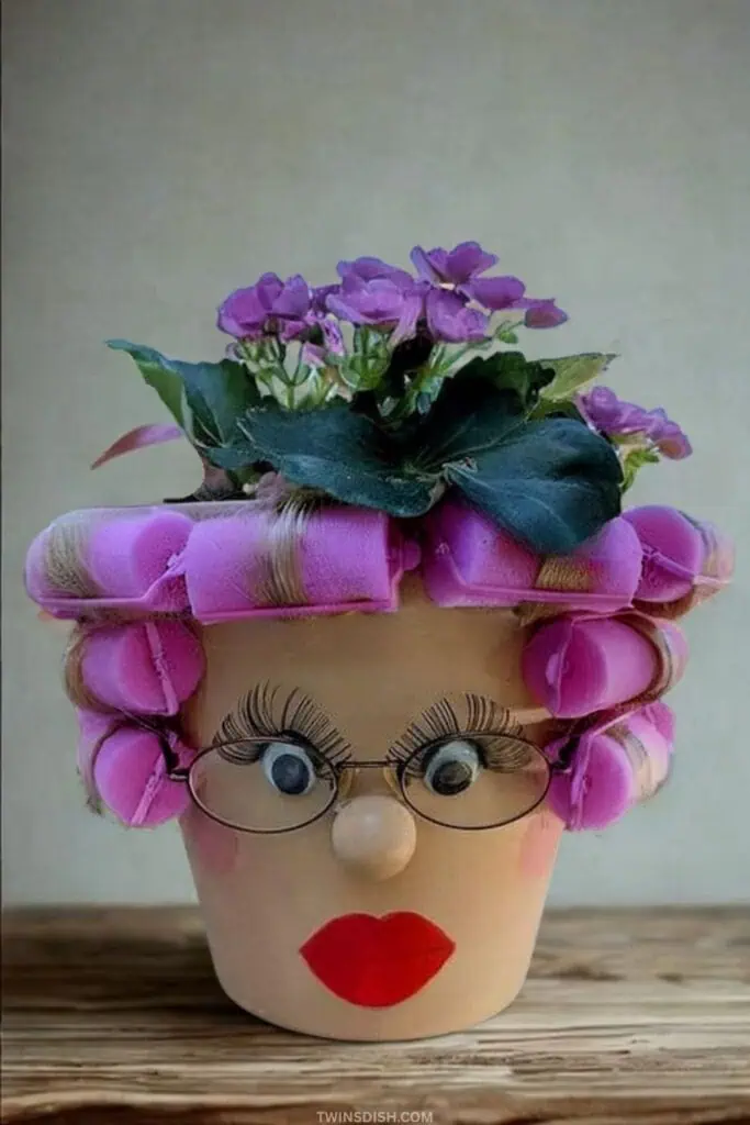 Funny summer crafts idea using a flower pot decorated like a lady with pink curlers, red lips, and purple flowers for hair — a creative DIY boredom buster for kids, teens, or adults.