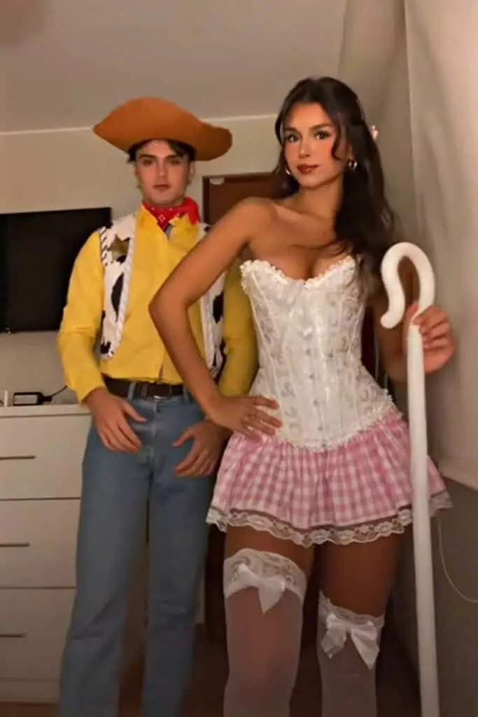 Woody and Little Bo Peep couples Halloween costume inspired by Toy Story, featuring Woody in a cowboy outfit and Bo Peep in a corset, pink gingham skirt, and shepherd’s staff.