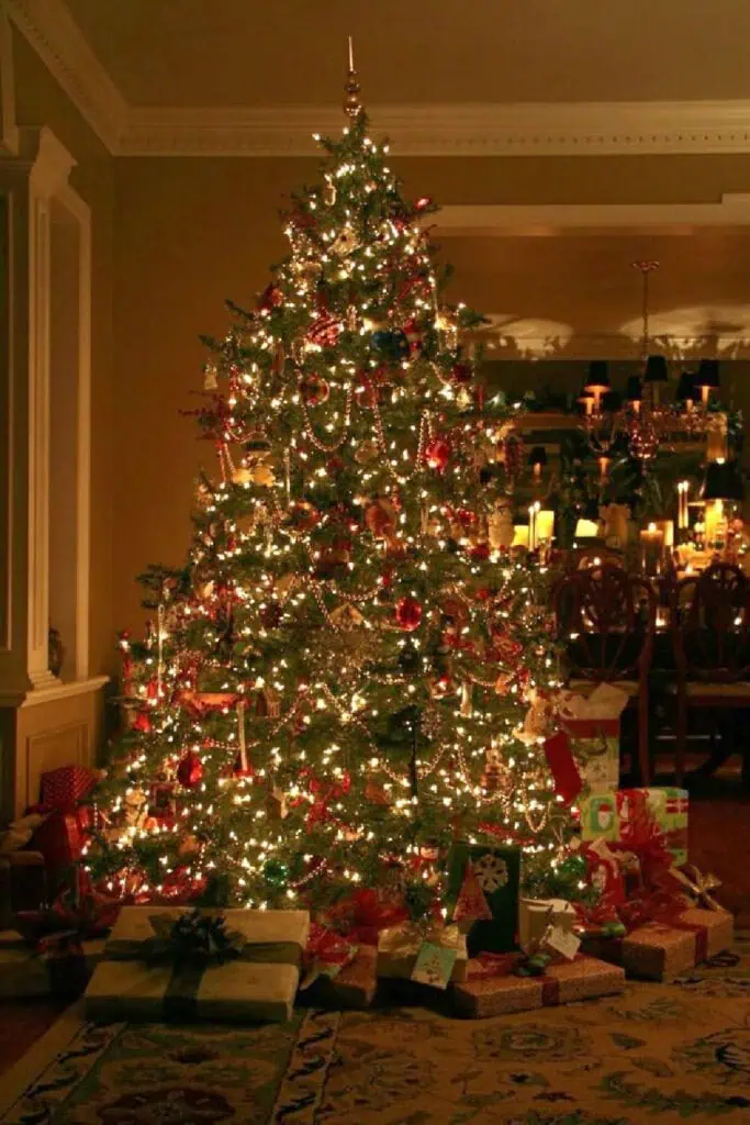Cozy 90s Christmas tree decorated with twinkling white lights, red and gold ornaments, and strands of beads, surrounded by wrapped presents in a warm candlelit living room.