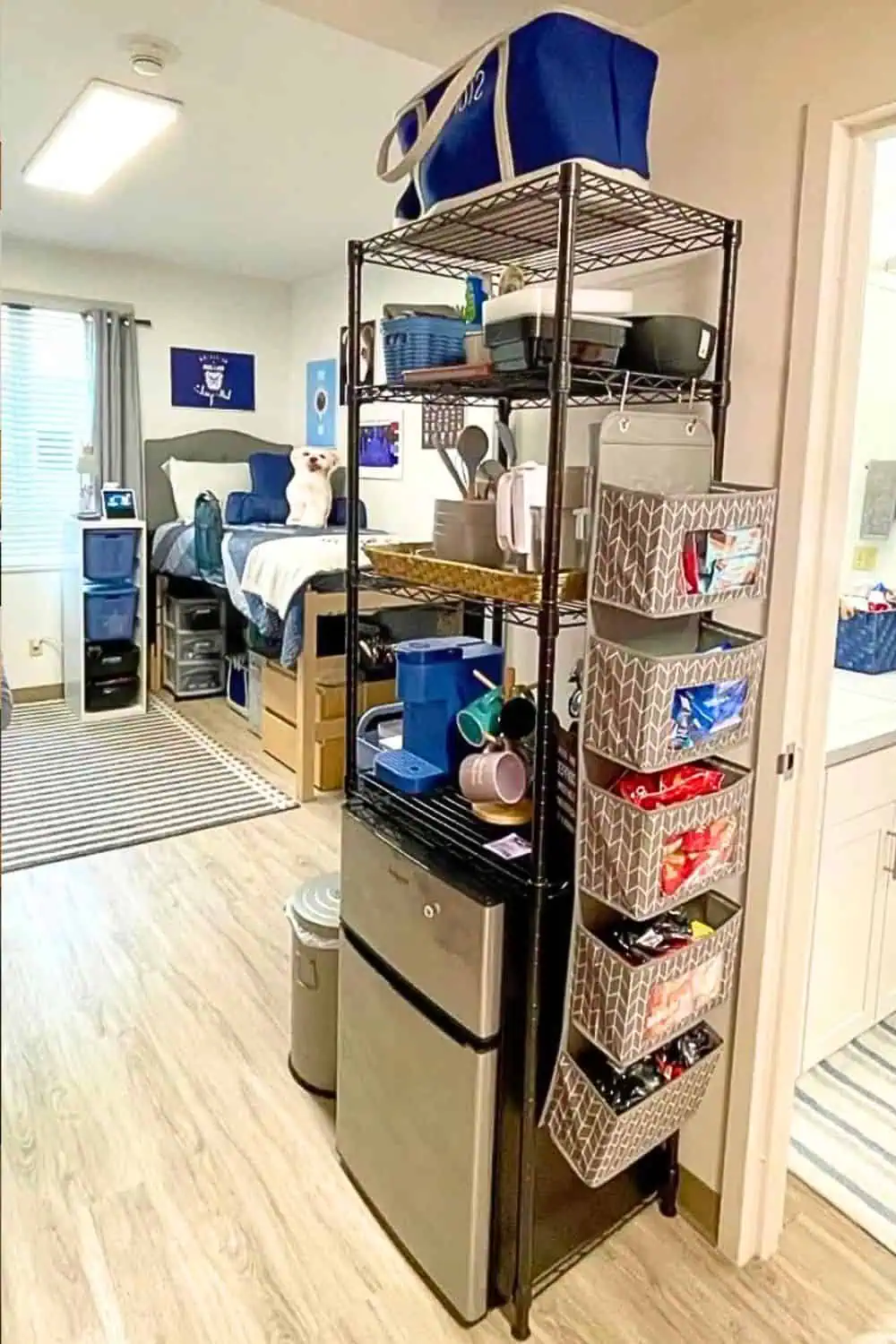 College dorm room with a compact kitchen setup including a mini fridge, coffee station, wire shelving unit, and hanging snack organizer — ideal for maximizing food storage and organization in small dorm spaces.