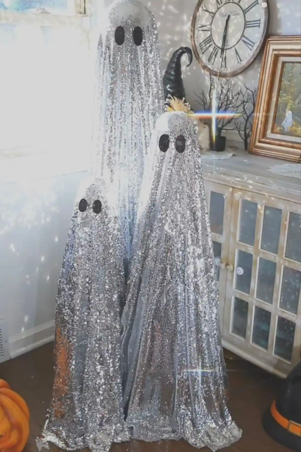 Three sparkly sequin ghost decorations in a cozy Halloween setup with pumpkins, a witch hat, and vintage-inspired decor — an easy DIY Halloween project made in 15 minutes or less.