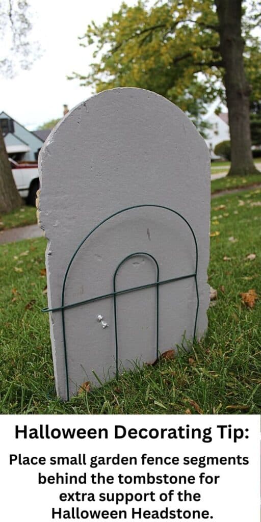 DIY cardboard tombstone outdoor Halloween decoration stabilized with Dollar Tree garden fencing for easy and affordable yard decor.