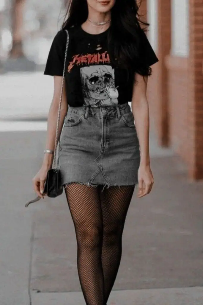 Cute fall outfit idea for teens featuring a black band tee, denim mini skirt, and fishnet tights styled with boots and a crossbody bag. A 90s-inspired look perfect for school, casual days, or going out.
