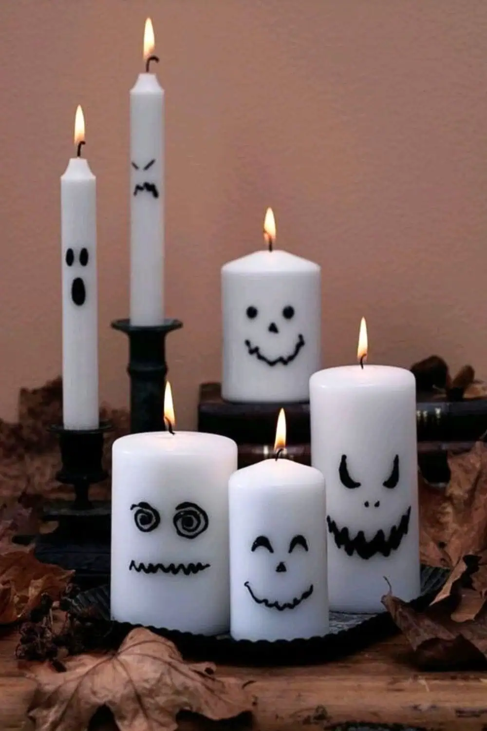 DIY Halloween ghost candles made from plain white candles with spooky faces drawn on using black marker. Cheap and easy Halloween décor idea.