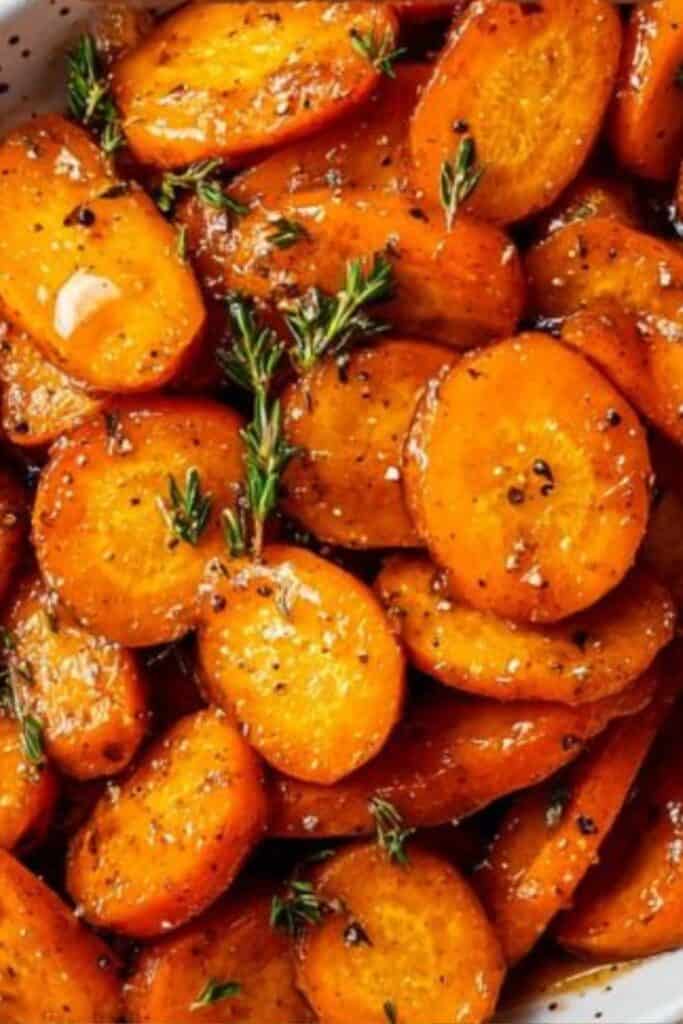A bowl of glossy honey glazed carrots garnished with herbs and cracked pepper. This quick 15-minute Thanksgiving side dish looks gourmet but is easy to make, perfect for holidays, weeknight dinners, or Friendsgiving meals.