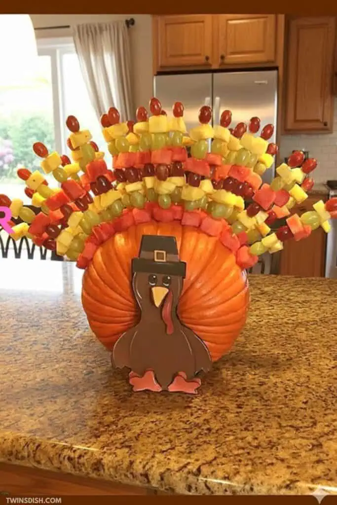 Thanksgiving fruit skewer turkey centerpiece made with colorful fruit kabobs and a pumpkin base — a fun, easy, and healthy dessert idea for kids and Thanksgiving parties.