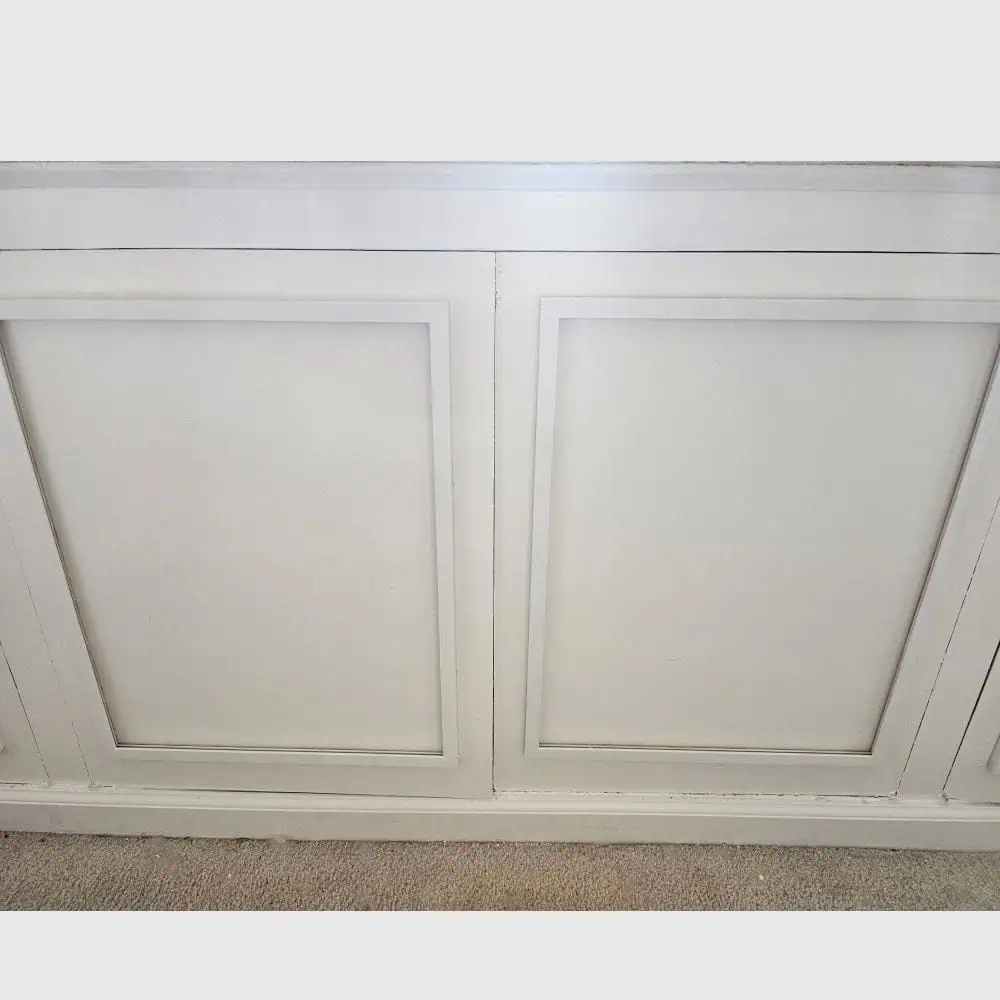 DIY renter-friendly wainscoting wall panels painted white above carpet flooring for an affordable apartment decor upgrade.