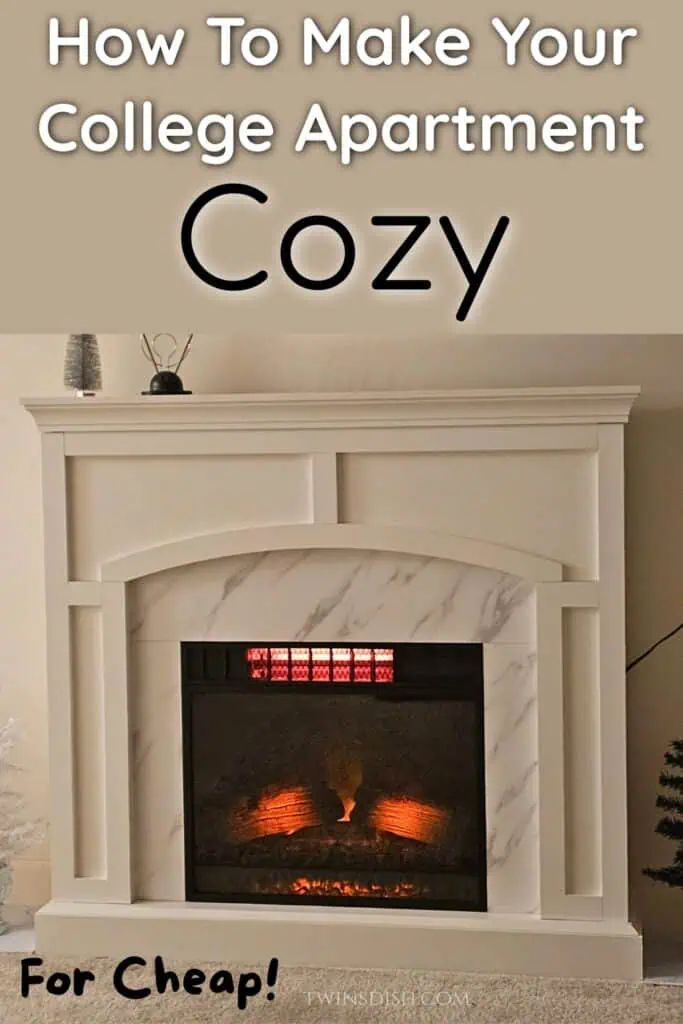 White electric fireplace with faux marble surround and orange glowing logs, styled with small decor items on the mantel, in a cozy college apartment living room
