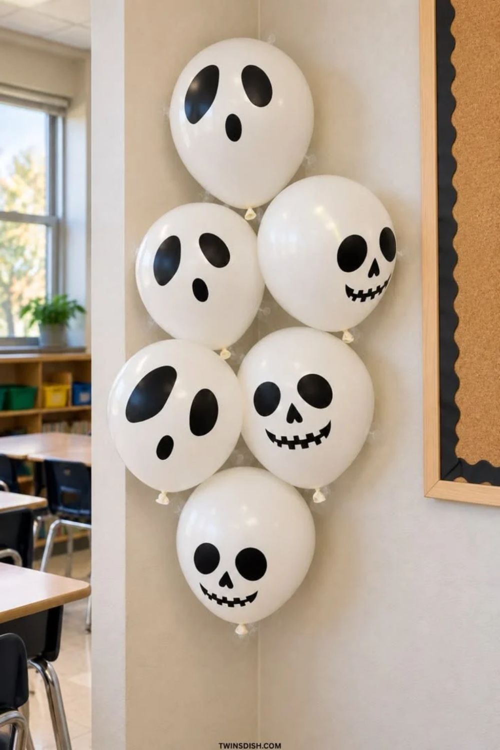 Easy DIY Halloween ghost and skeleton balloons made with white balloons and black spooky faces, displayed on a classroom wall. Cute, budget-friendly Halloween decorations for kids, school parties, and last-minute Halloween decor.