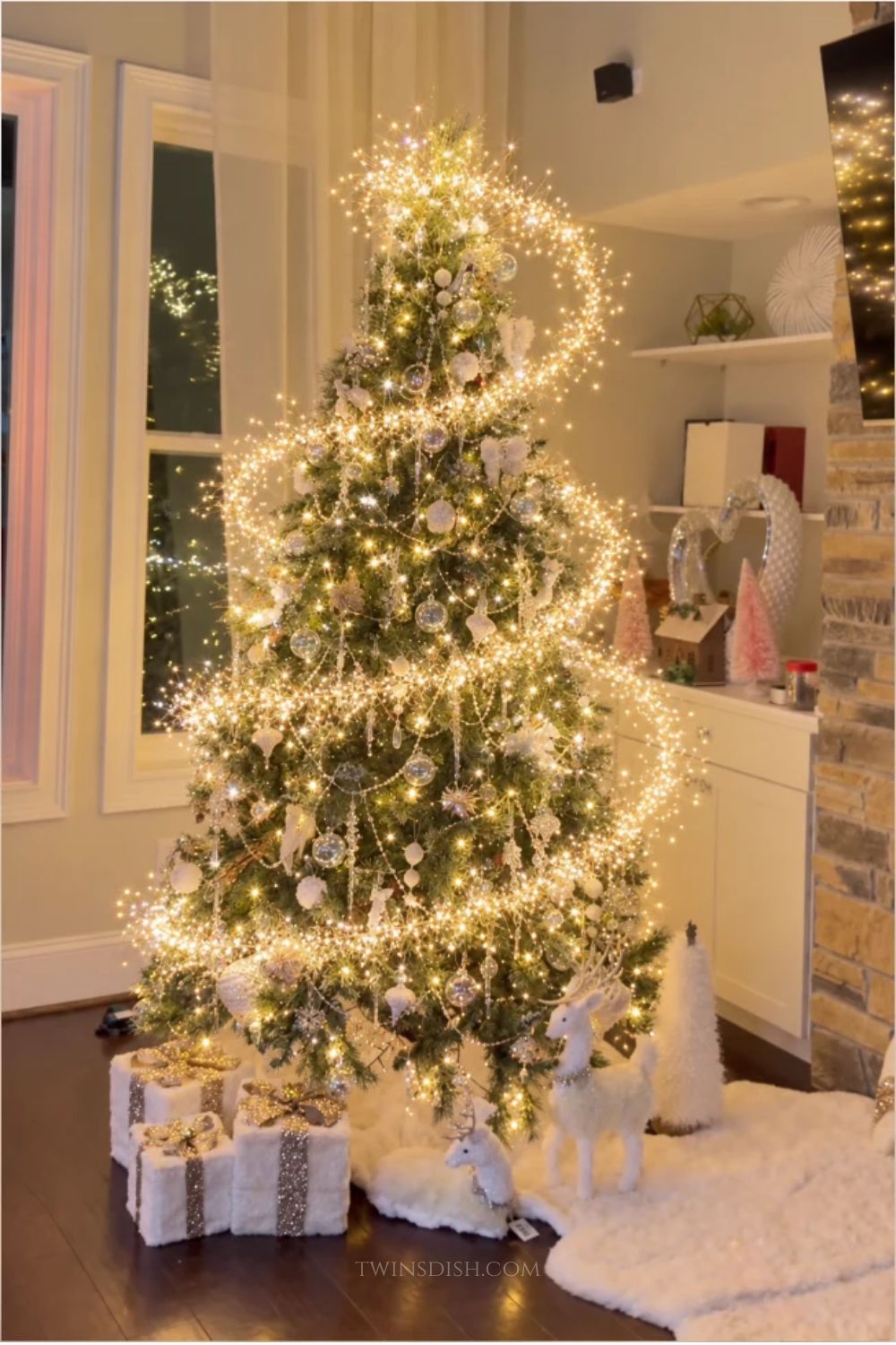 Cinderella-inspired Christmas tree with warm white firecracker cluster lights spiraling around clear glass ornaments, crystal icicles, and elegant white and gold decorations.