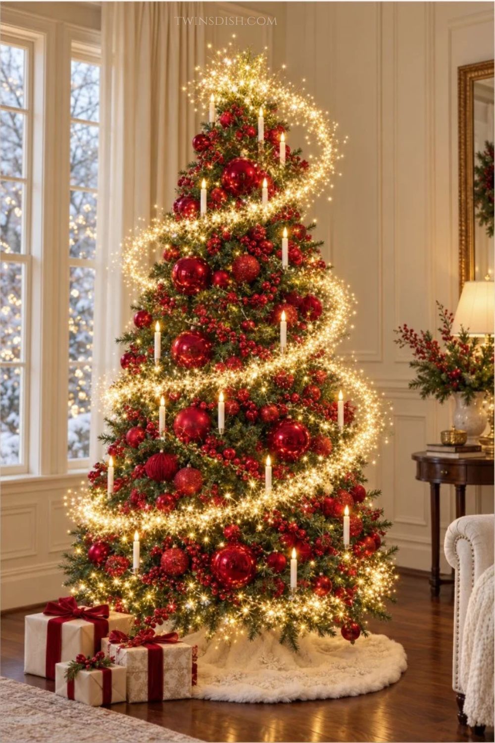 Elegant red Christmas tree decorated with oversized red ornaments, red berry garland, warm white spiral cluster lights, and candle-style lights in a bright traditional living room.