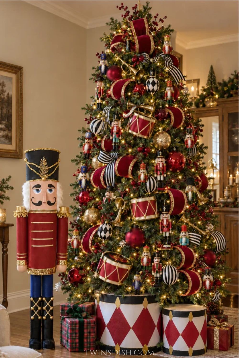 Nutcracker-themed Christmas tree decorated with miniature wooden nutcracker soldiers, red velvet ribbon, gold accents, black-and-white ornaments, toy drums, brass horns, and warm white lights. A large DIY nutcracker stands beside the tree.