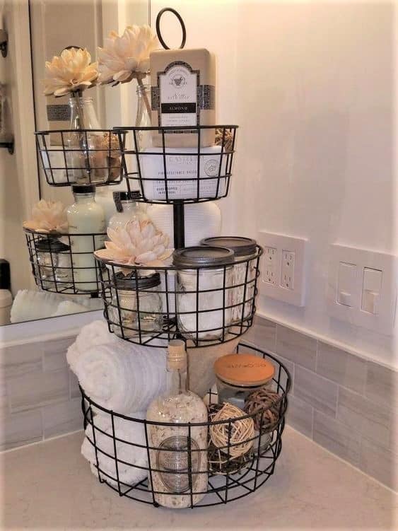 The best easy DIY Farmhouse small Bathroom decor ideas on a budget for apartments using tiered tray basket to organize counter top and give extra storage.